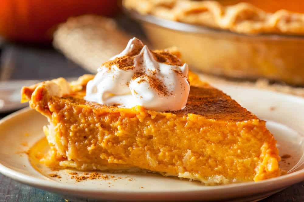 Slice of healthy pumpkin pie with a creamy orange filling and a dollop of yogurt on a plate