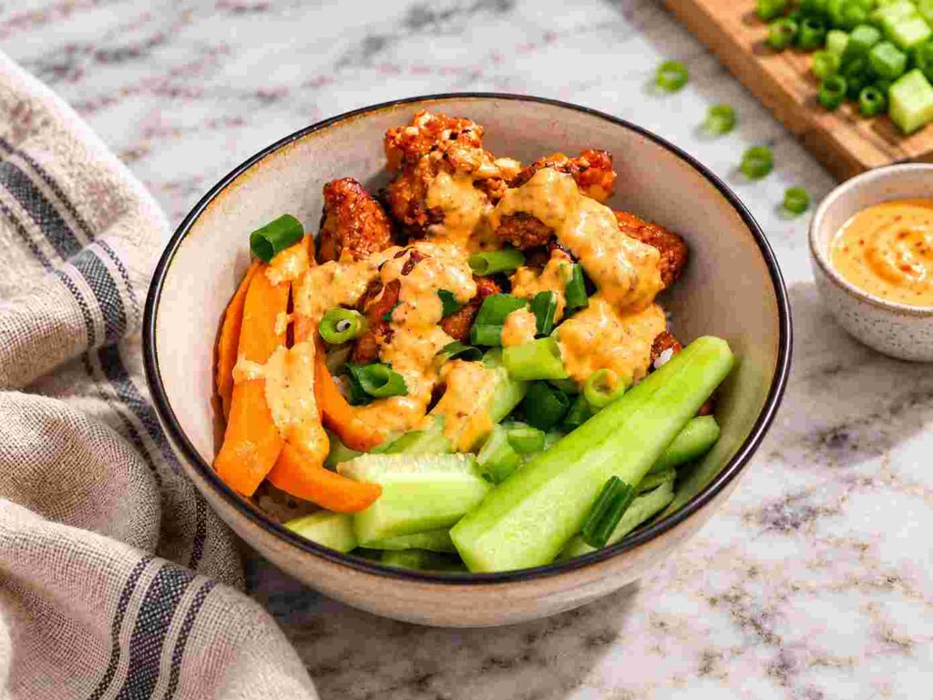 Air fryer bang bang salmon bowl with cucumber, carrots, green onions, and creamy spicy sauce